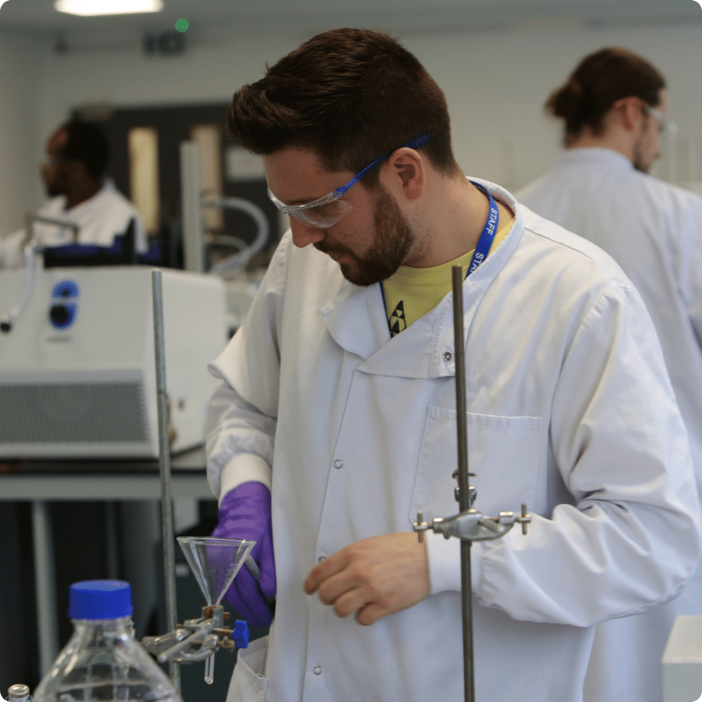 Male scientist with brown hair and beard wears a white lab coat in Nanopharm's OINDP development laboratory.